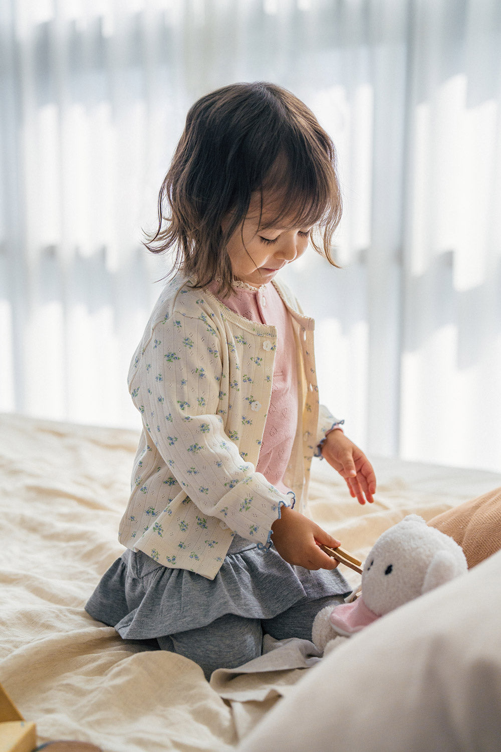 Toddler girl playing in Avauma Aileen Bloom Cardigan, soft ribbed cotton cardigan with vintage floral pattern, perfect for baby outfits. Toddler girl playing in Avauma Aileen Bloom Cardigan, soft ribbed cotton cardigan with vintage floral pattern, perfect for baby outfits.