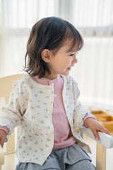 Baby girl smiling in Avauma Aileen Bloom Cardigan, cozy knit floral baby cardigan for spring and fall wardrobe. Baby girl smiling in Avauma Aileen Bloom Cardigan, cozy knit floral baby cardigan for spring and fall wardrobe.