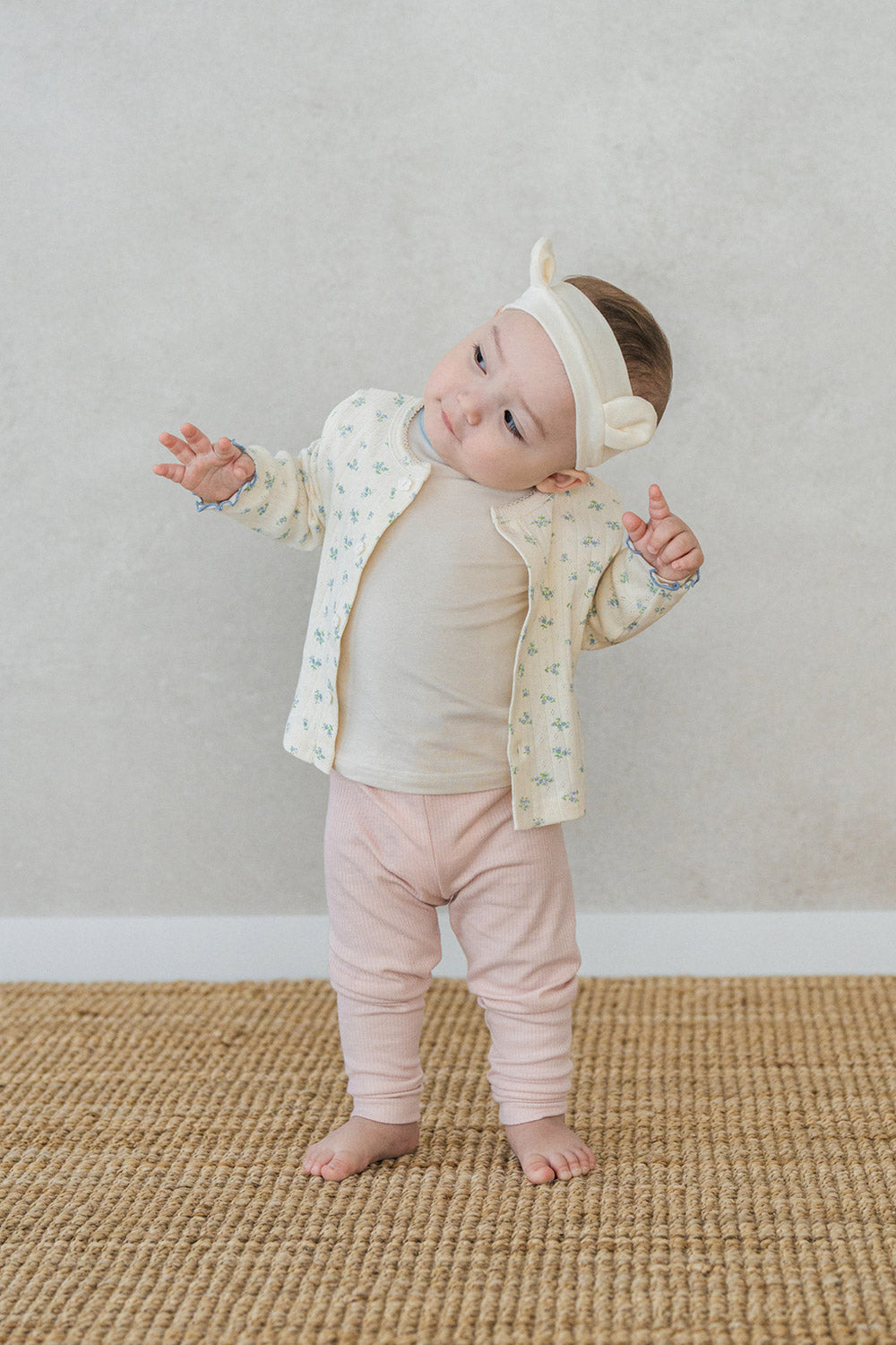 Baby girl posing in Avauma Aileen Bloom Cardigan, vintage-inspired floral cardigan for babies and toddlers, soft and stylish. Baby girl posing in Avauma Aileen Bloom Cardigan, vintage-inspired floral cardigan for babies and toddlers, soft and stylish.