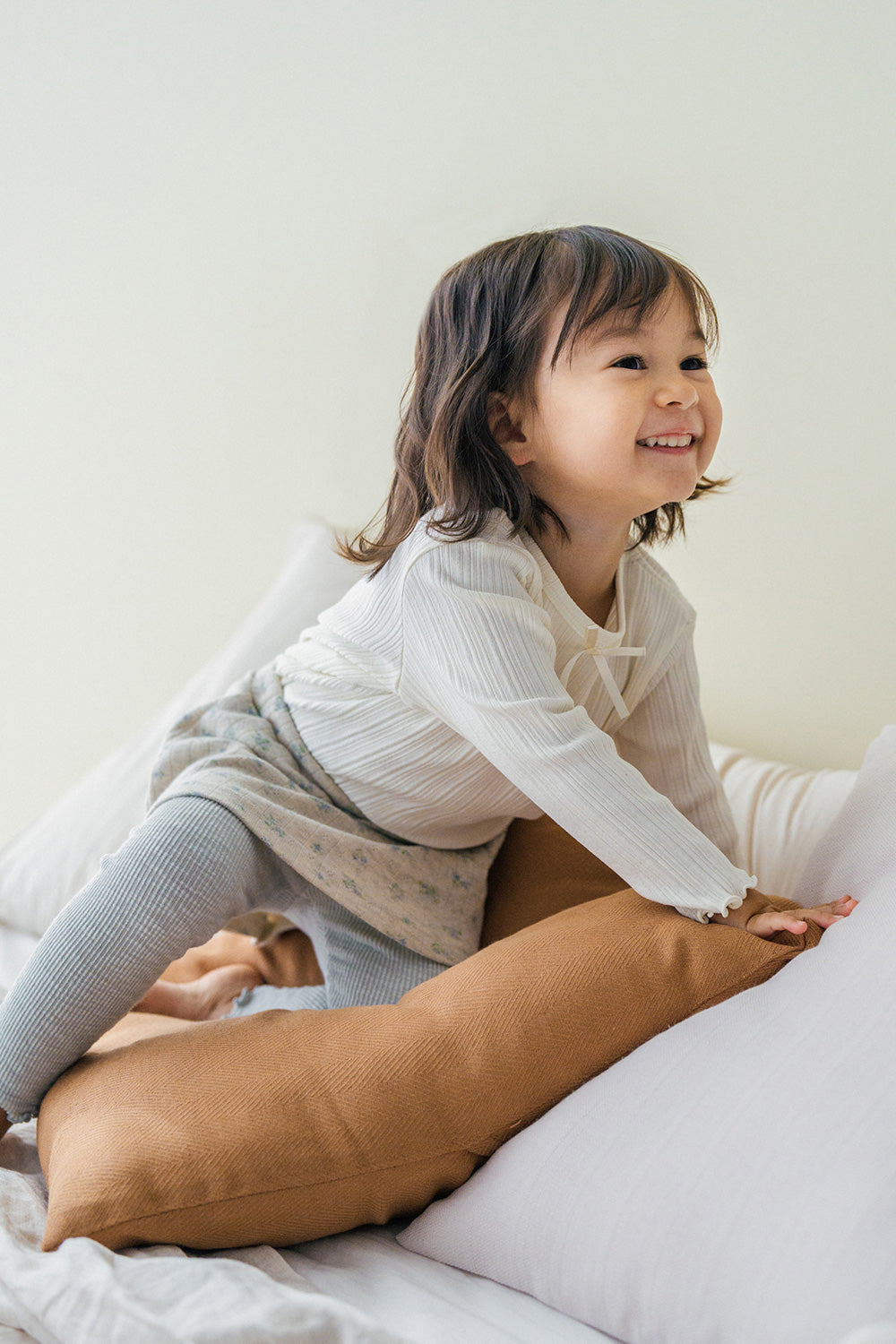 Little girl wearing Avauma Chloe Ribbon T-shirt in Cotton Cream, styled with a floral skirt and ribbed leggings. Little girl wearing Avauma Chloe Ribbon T-shirt in Cotton Cream, styled with a floral skirt and ribbed leggings.