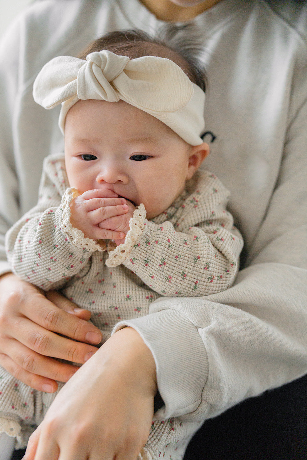 Baby in the Mellow Rose bodysuit held by a caregiver – a practical design enhanced by lace around the neckline and cuffs. Baby in the Mellow Rose bodysuit held by a caregiver – a practical design enhanced by lace around the neckline and cuffs.