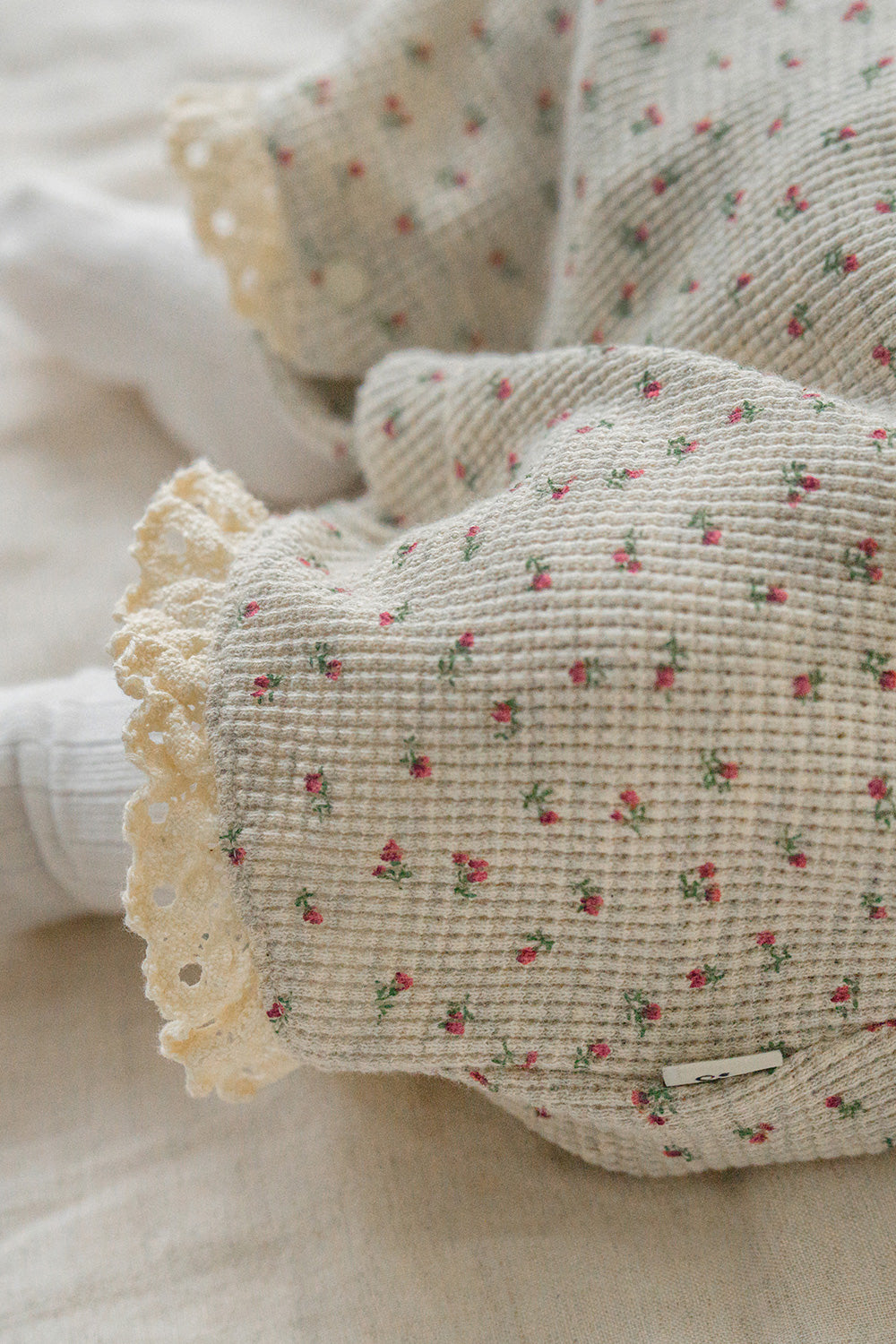 Close-up of the lower portion of the Mellow Rose bodysuit – a subtle rose pattern and lace hem add a charming accent to this baby romper. Close-up of the lower portion of the Mellow Rose bodysuit – a subtle rose pattern and lace hem add a charming accent to this baby romper.