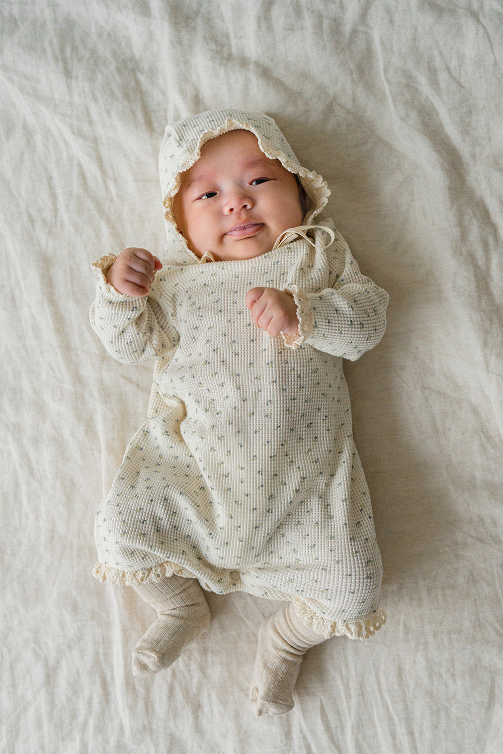 Baby in the Lumiere Classic Blossom Bodysuit being held – highlighting the soft knit texture and charming floral pattern Baby in the Lumiere Classic Blossom Bodysuit being held – highlighting the soft knit texture and charming floral pattern