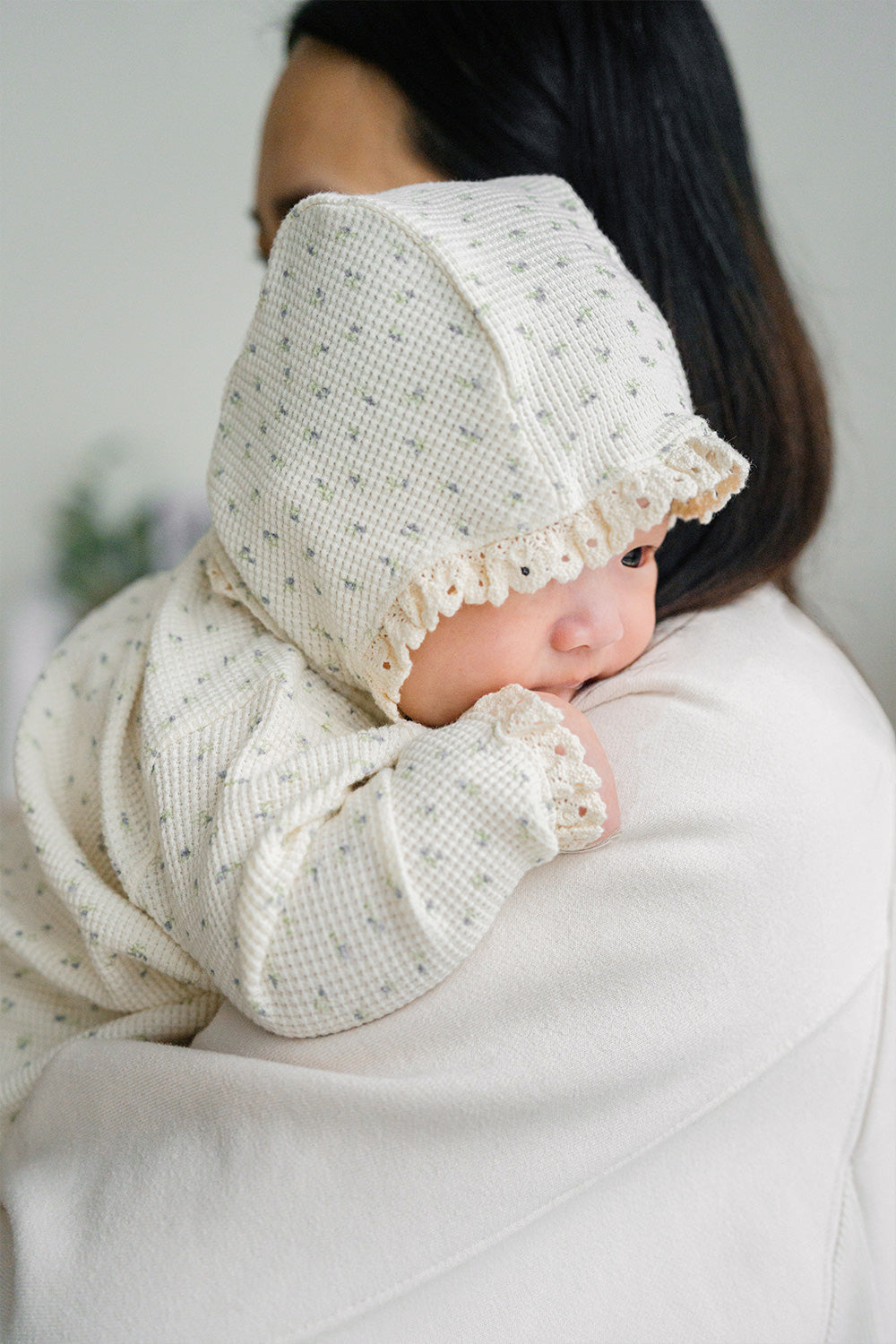 Baby wearing the Lumiere Classic Blossom Bodysuit with a headband – featuring elegant lace details and a sweet floral mood Baby wearing the Lumiere Classic Blossom Bodysuit with a headband – featuring elegant lace details and a sweet floral mood