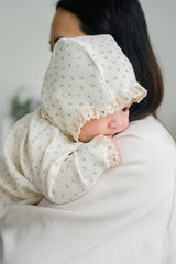 Baby wearing the Lumiere Classic Blossom Bodysuit with a headband – featuring elegant lace details and a sweet floral mood Baby wearing the Lumiere Classic Blossom Bodysuit with a headband – featuring elegant lace details and a sweet floral mood