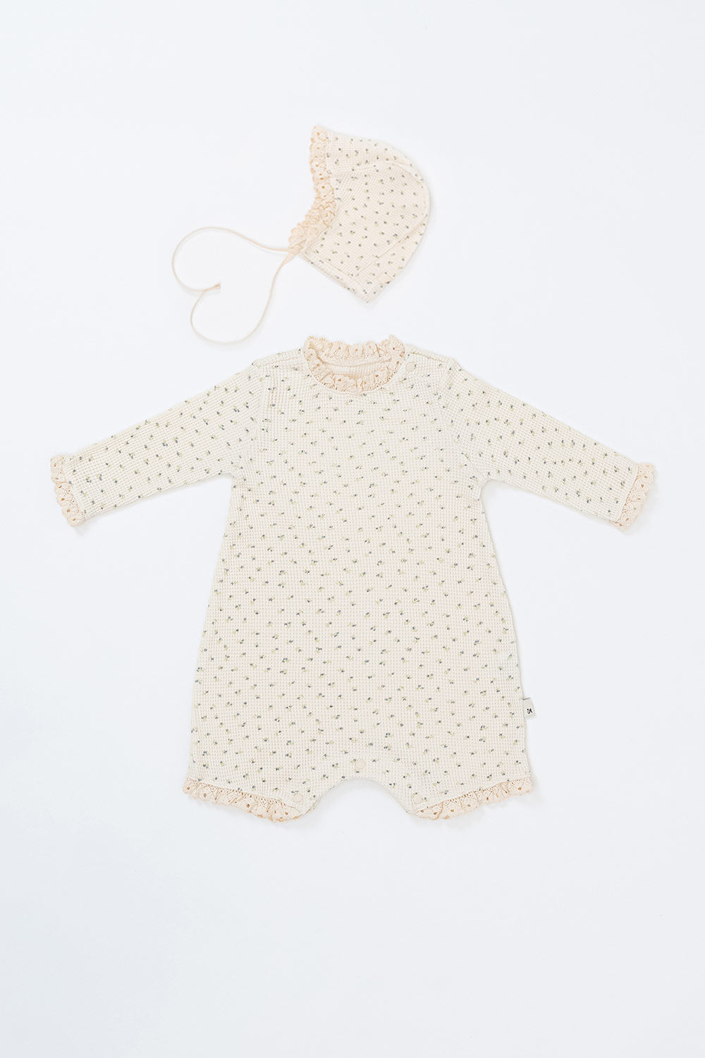 Front view of the Lumiere Bodysuit in Classic Blossom – a long-sleeve baby romper featuring lace trimming and a matching bonnet Front view of the Lumiere Bodysuit in Classic Blossom – a long-sleeve baby romper featuring lace trimming and a matching bonnet