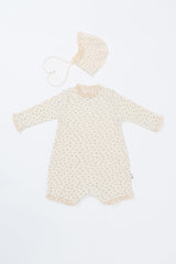 Front view of the Lumiere Bodysuit in Classic Blossom – a long-sleeve baby romper featuring lace trimming and a matching bonnet Front view of the Lumiere Bodysuit in Classic Blossom – a long-sleeve baby romper featuring lace trimming and a matching bonnet