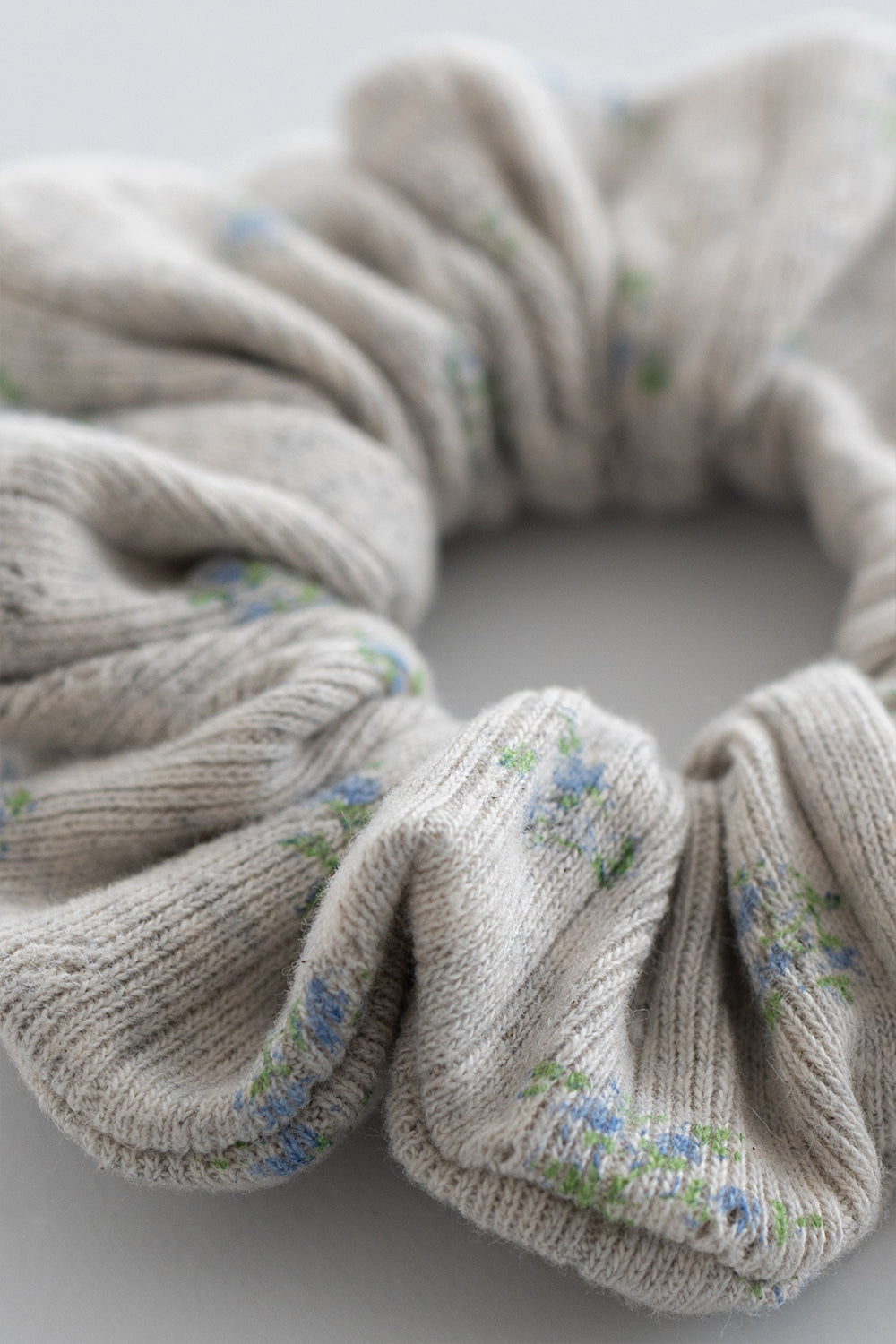 Close-up of pebble green ribbed scrunchie with pastel blue and green floral pattern – Avauma Close-up of pebble green ribbed scrunchie with pastel blue and green floral pattern – Avauma