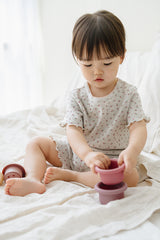 Toddler in Avauma Mellow Days Set in Berry Cream, sitting on a bed and stacking purple cups
ALT Toddler in Avauma Mellow Days Set in Berry Cream, sitting on a bed and stacking purple cups
ALT