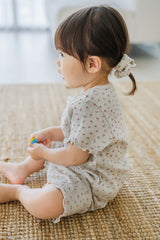 Side view of toddler sitting on a rug, hair tied with matching scrunchie, wearing Berry Cream Mellow Days Set Side view of toddler sitting on a rug, hair tied with matching scrunchie, wearing Berry Cream Mellow Days Set