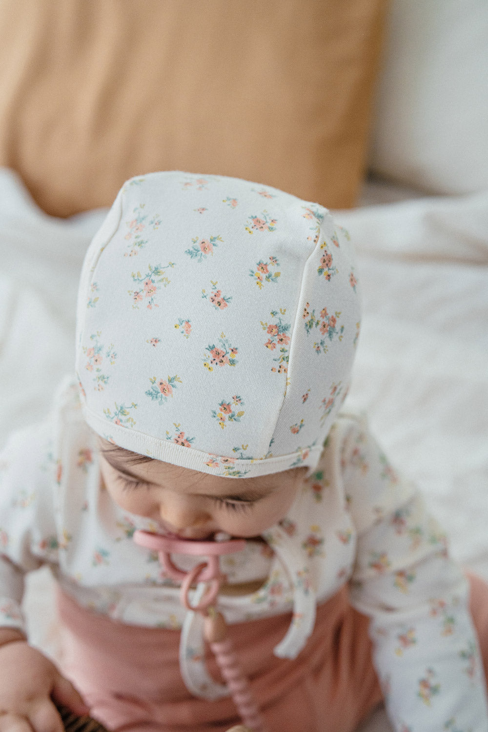 Top-down shot of a baby wearing the Cream Floral bonnet – emphasizing the bright color palette and breathable fabric for comfort Top-down shot of a baby wearing the Cream Floral bonnet – emphasizing the bright color palette and breathable fabric for comfort