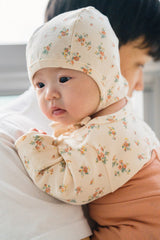 Baby in the Cream Floral bodysuit held by a caregiver – featuring a soft feel and secure wrap design suitable for newborns and infants Baby in the Cream Floral bodysuit held by a caregiver – featuring a soft feel and secure wrap design suitable for newborns and infants