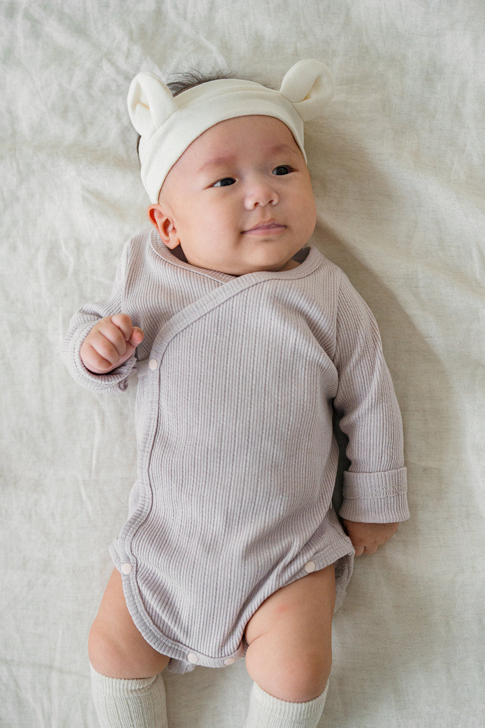 Baby dressed in the lavender haze Avauma Selina Babysuit, styled with a playful ear headband, showcasing a snug fit and soft material for everyday wear.
 Baby dressed in the lavender haze Avauma Selina Babysuit, styled with a playful ear headband, showcasing a snug fit and soft material for everyday wear.