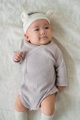 Baby dressed in the lavender haze Avauma Selina Babysuit, styled with a playful ear headband, showcasing a snug fit and soft material for everyday wear.
 Baby dressed in the lavender haze Avauma Selina Babysuit, styled with a playful ear headband, showcasing a snug fit and soft material for everyday wear.