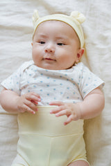 Happy newborn baby looking at camera in Avauma Baby Hug Setup Lime Bloom. Cheerful infant in yellow soft outfit. Happy newborn baby looking at camera in Avauma Baby Hug Setup Lime Bloom. Cheerful infant in yellow soft outfit.