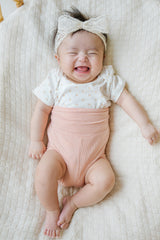 Adorable newborn baby model wearing Avauma Baby Hug Setup in Peach Blossom. Sweet pink baby romper on a white studio background. Adorable newborn baby model wearing Avauma Baby Hug Setup in Peach Blossom. Sweet pink baby romper on a white studio background.