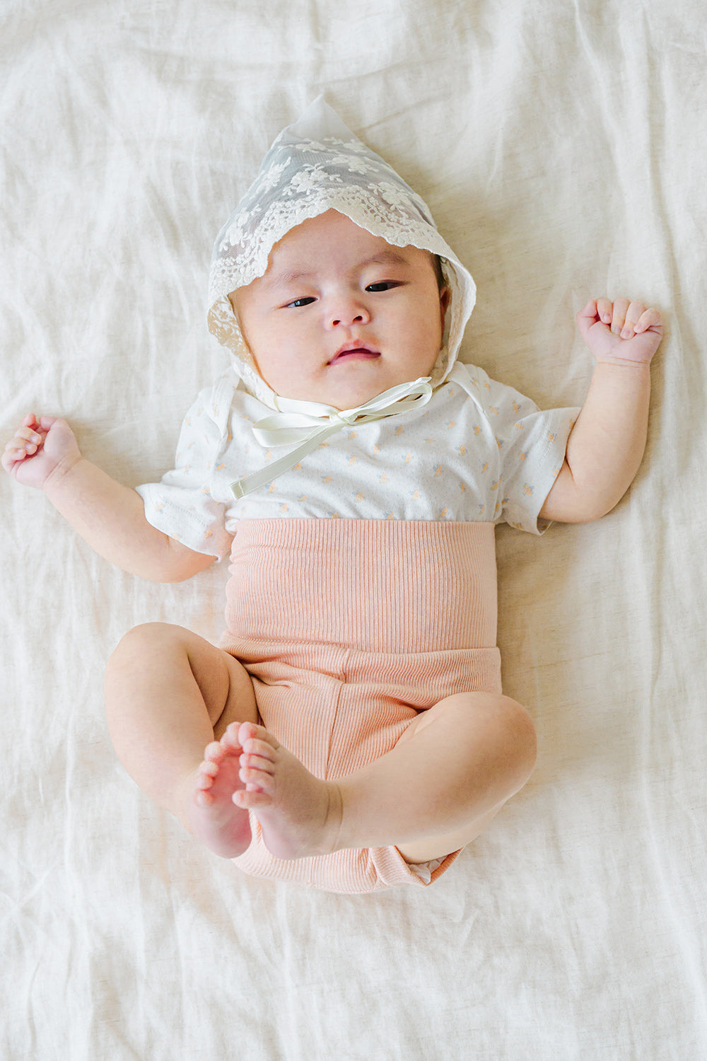Newborn baby looking up in Avauma Baby Hug Setup Peach Blossom. Precious infant model in a soft pink one-piece outfit. Newborn baby looking up in Avauma Baby Hug Setup Peach Blossom. Precious infant model in a soft pink one-piece outfit.