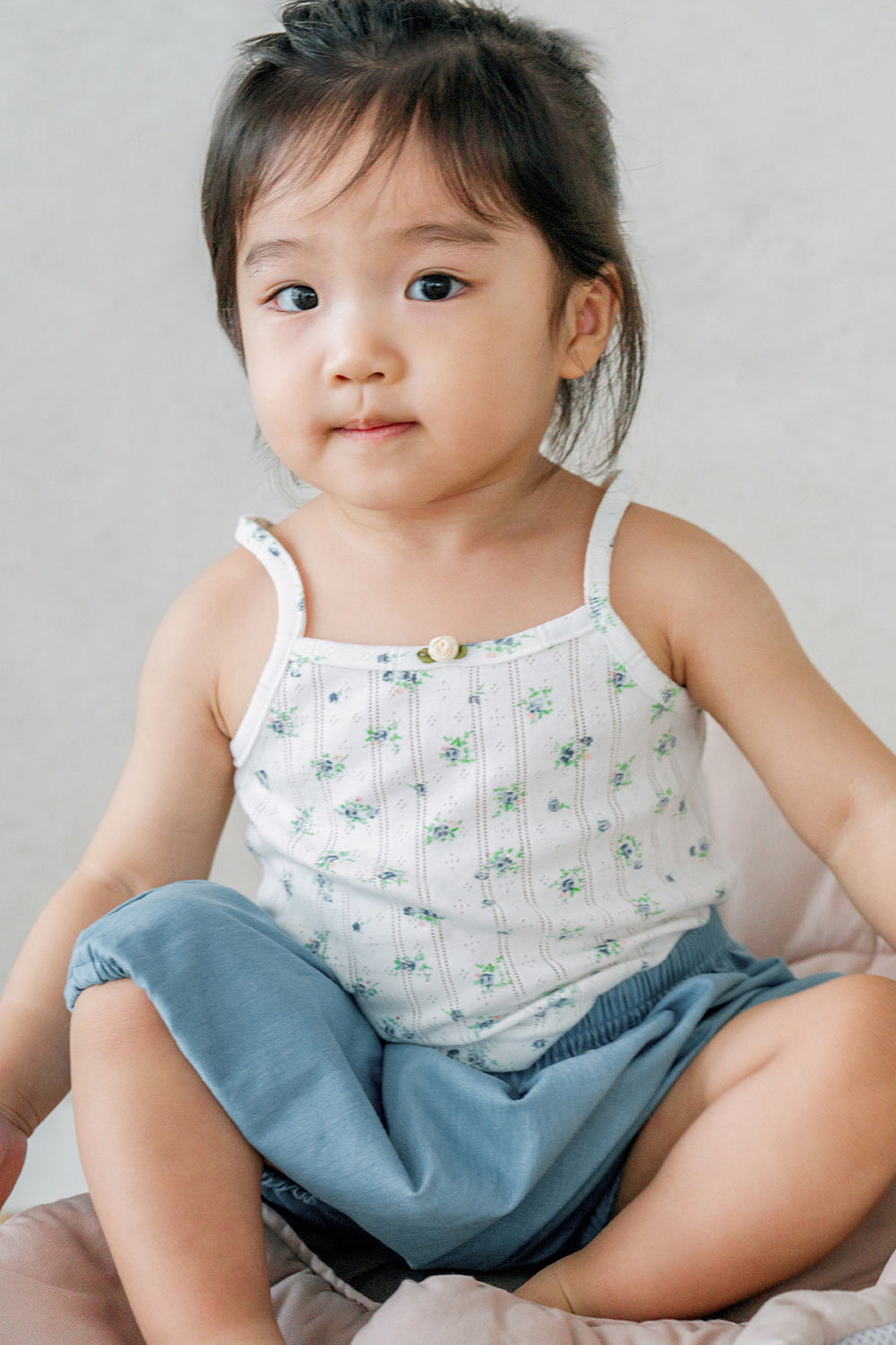 Toddler sitting in Avauma Cloud Denim Bloomer Fadeblue. Child in a floral tank top and light blue denim-look bloomers. Toddler sitting in Avauma Cloud Denim Bloomer Fadeblue. Child in a floral tank top and light blue denim-look bloomers.
