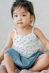 Toddler sitting in Avauma Cloud Denim Bloomer Fadeblue. Child in a floral tank top and light blue denim-look bloomers. Toddler sitting in Avauma Cloud Denim Bloomer Fadeblue. Child in a floral tank top and light blue denim-look bloomers.