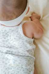 Close-up of Avauma Lily Sleeveless Bodysuit Cream Blue. Detail of baby's shoulder and back in a white romper with delicate blue floral print.
Close-up of Avauma Lily Sleeveless Bodysuit Cream Blue. Detail of baby's shoulder and back in a white romper with delicate blue floral print.