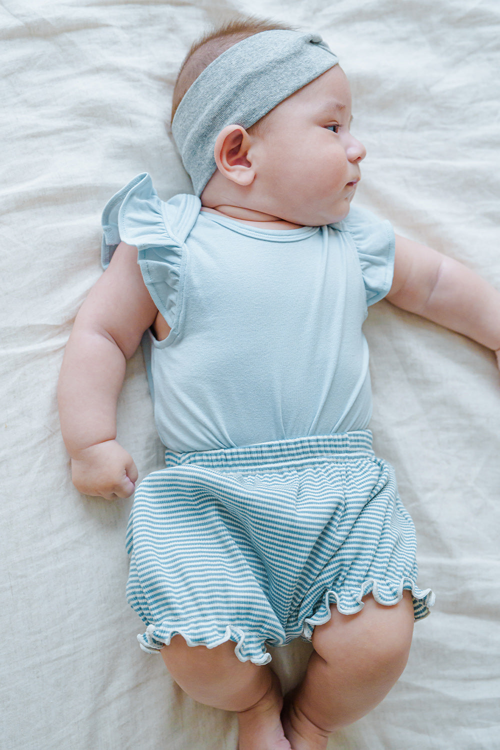 Cute baby model wearing Avauma Mellow Stripe Set Aquamint. Newborn in light blue striped outfit, comfortable baby clothes. Cute baby model wearing Avauma Mellow Stripe Set Aquamint. Newborn in light blue striped outfit, comfortable baby clothes.