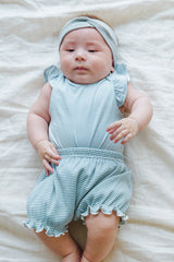 Happy infant in Avauma Mellow Stripe Set Aquamint. Baby smiling and looking at camera in a soft blue striped romper. Happy infant in Avauma Mellow Stripe Set Aquamint. Baby smiling and looking at camera in a soft blue striped romper.