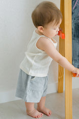 Baby boy wearing Avauma Pocket Shorts in Green Tea Milk and sleeveless top, standing by a wooden rail
Baby boy wearing Avauma Pocket Shorts in Green Tea Milk and sleeveless top, standing by a wooden rail