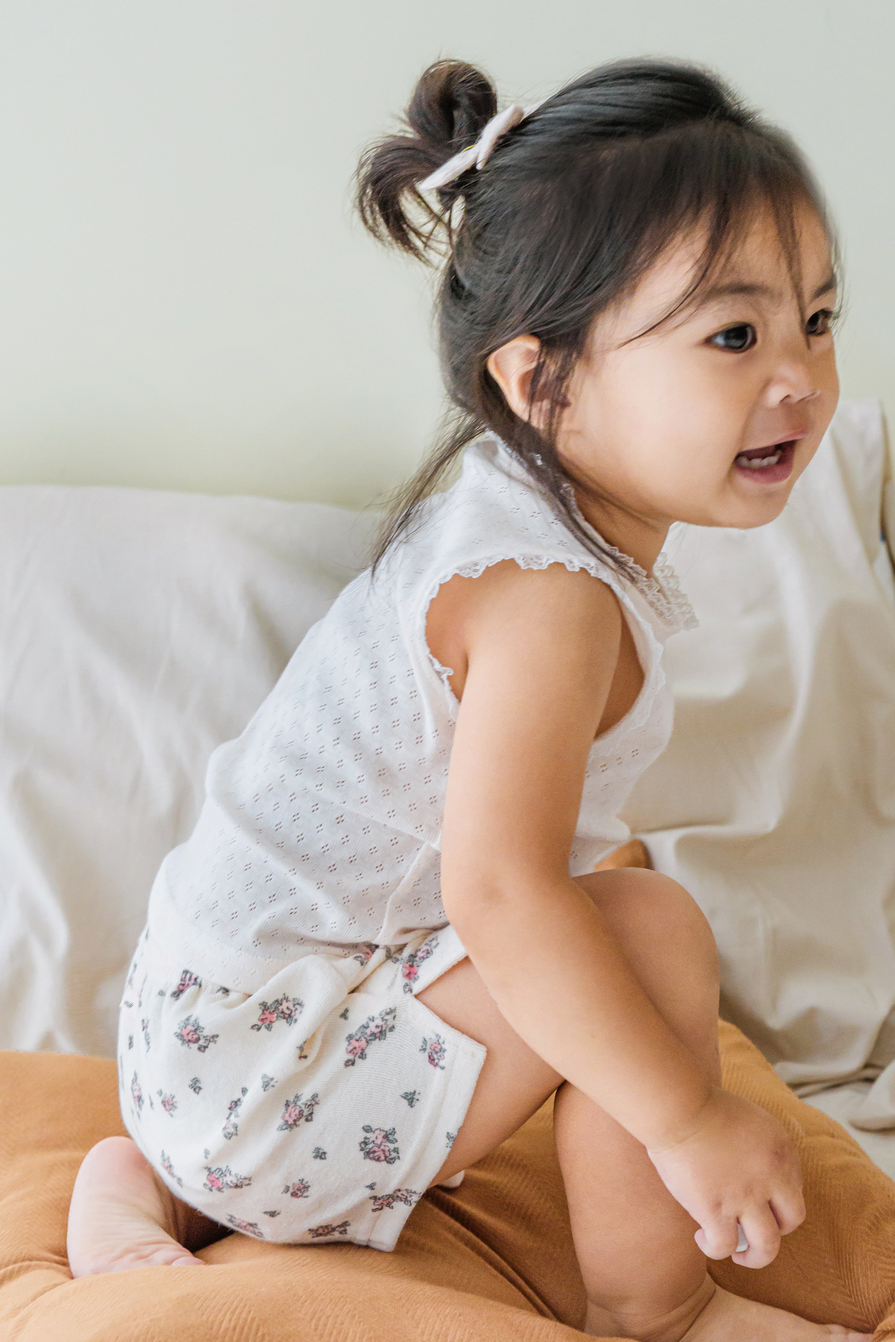 Side view of baby in Avauma vanilla cream tank top and floral shorts – soft dailywear Side view of baby in Avauma vanilla cream tank top and floral shorts – soft dailywear