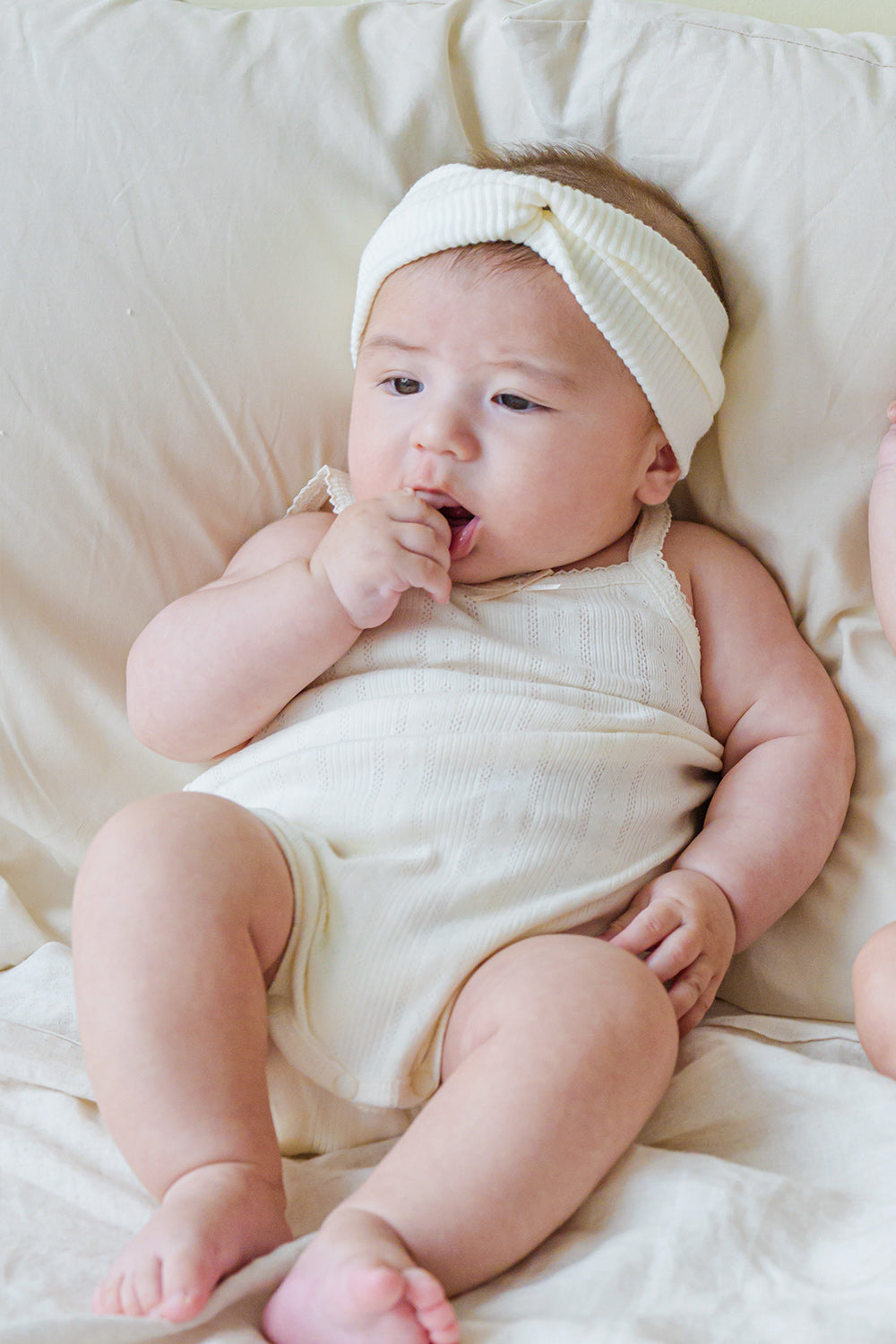Sweet baby wearing Avauma Summer Picot Sleeveless Bodysuit Buttermilk. Infant sitting up in a comfortable white ribbed bodysuit and twisted headband.
Sweet baby wearing Avauma Summer Picot Sleeveless Bodysuit Buttermilk. Infant sitting up in a comfortable white ribbed bodysuit and twisted headband.