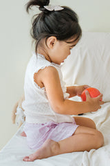Toddler sitting in Avauma Sunny Stripe Pants Lotus Pink. Child holding a fruit, wearing light pink ribbed shorts and a white top, side view.
Toddler sitting in Avauma Sunny Stripe Pants Lotus Pink. Child holding a fruit, wearing light pink ribbed shorts and a white top, side view.
