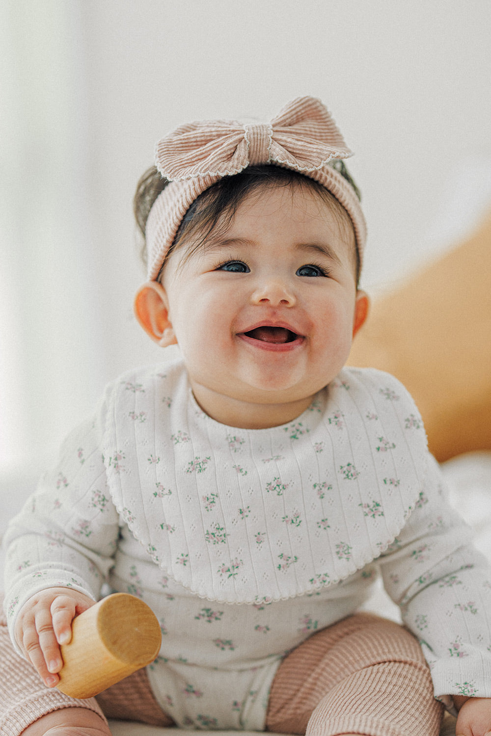 Front view of baby girl in Avauma Baby Blush ribbon headband and printed white bodysuit
 Front view of baby girl in Avauma Baby Blush ribbon headband and printed white bodysuit