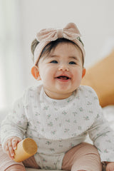 Front view of baby girl in Avauma Baby Blush ribbon headband and printed white bodysuit
 Front view of baby girl in Avauma Baby Blush ribbon headband and printed white bodysuit