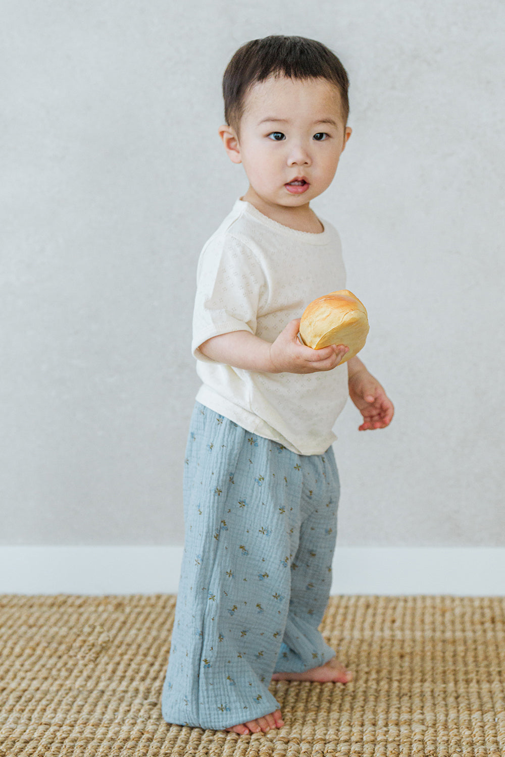 Toddler boy wearing Avauma Breeze Jogger Pants - deepblue flower, holding a toy while standing. Toddler boy wearing Avauma Breeze Jogger Pants - deepblue flower, holding a toy while standing.