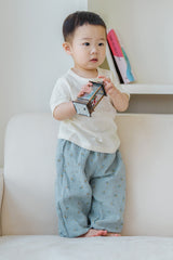 Baby boy sitting on a sofa in Avauma Breeze Jogger Pants - deepblue flower, holding a juice box. Baby boy sitting on a sofa in Avauma Breeze Jogger Pants - deepblue flower, holding a juice box.