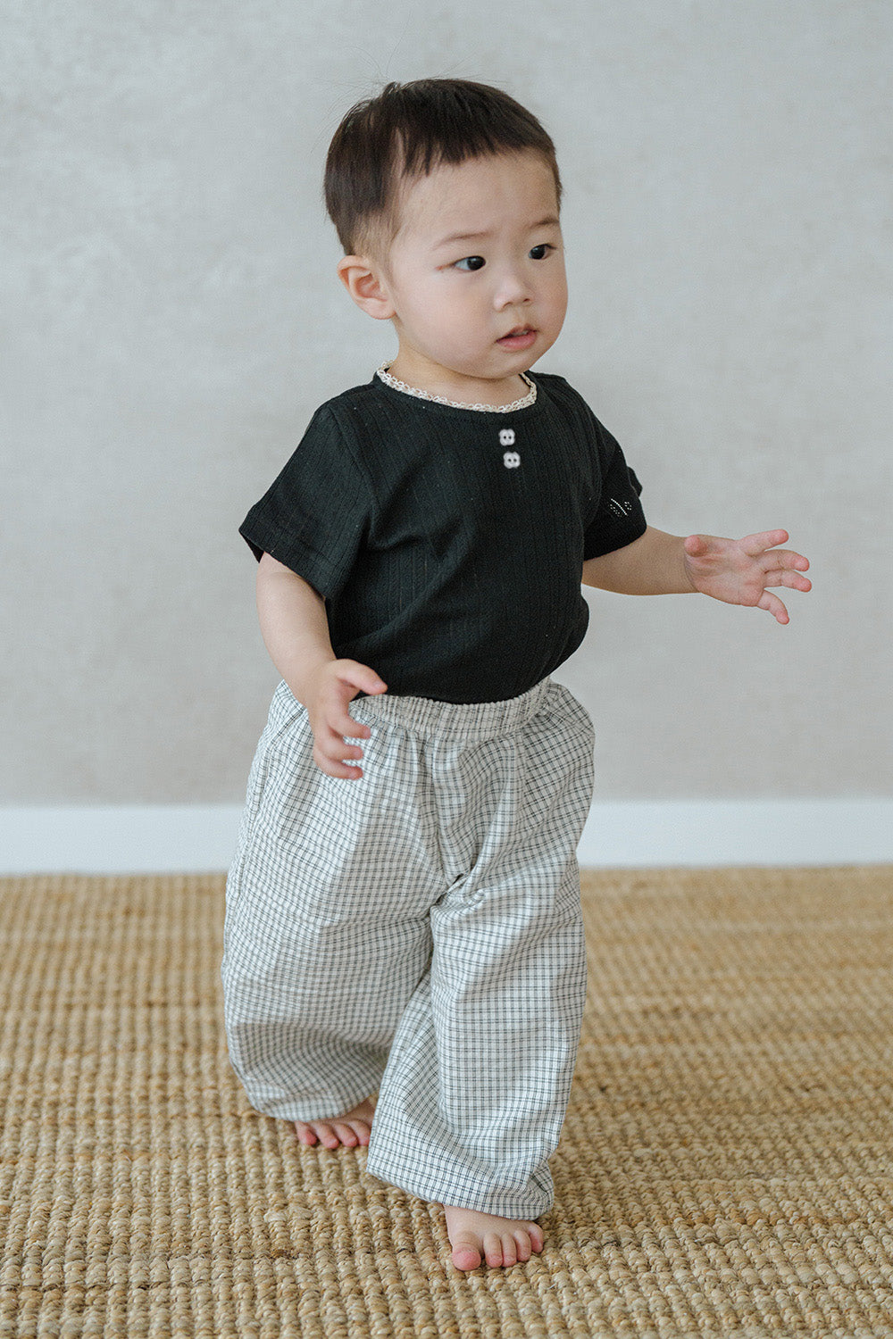 Toddler wearing Avauma Breeze Jogger Pants in vintage check, standing on mat with black top. Toddler wearing Avauma Breeze Jogger Pants in vintage check, standing on mat with black top.