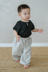 Toddler wearing Avauma Breeze Jogger Pants in vintage check, standing on mat with black top. Toddler wearing Avauma Breeze Jogger Pants in vintage check, standing on mat with black top.