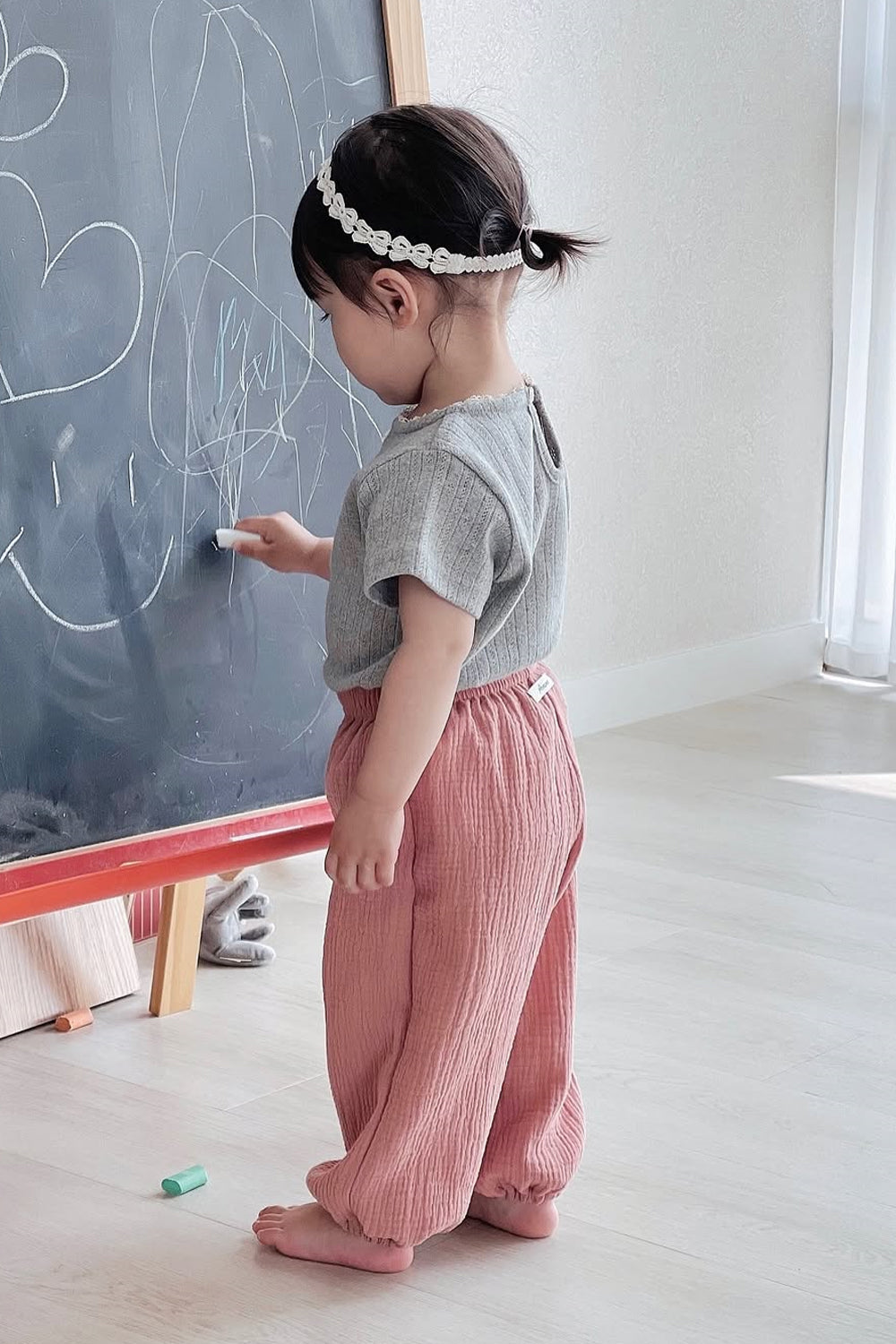 Toddler wearing Avauma Breeze Jogger Pants in rose wood, standing and drawing on chalkboard. Toddler wearing Avauma Breeze Jogger Pants in rose wood, standing and drawing on chalkboard.