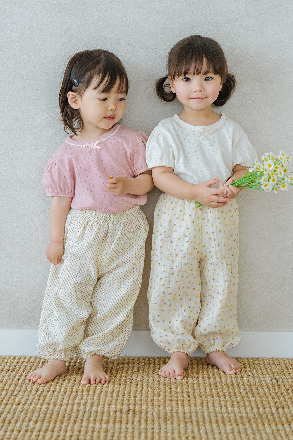 Two girls wearing Avauma Breeze Jogger Pants - roseberry cream, standing together holding flowers. Two girls wearing Avauma Breeze Jogger Pants - roseberry cream, standing together holding flowers.