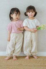 Two girls wearing Avauma Breeze Jogger Pants - roseberry cream, standing together holding flowers. Two girls wearing Avauma Breeze Jogger Pants - roseberry cream, standing together holding flowers.