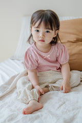 Baby girl lounging in Avauma Breeze Jogger Pants - roseberry cream, natural light and cozy atmosphere. Baby girl lounging in Avauma Breeze Jogger Pants - roseberry cream, natural light and cozy atmosphere.