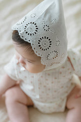 Top view of baby girl wearing Avauma Clare Bonnet - Cotton Cream, showing flower-patterned eyelet design Top view of baby girl wearing Avauma Clare Bonnet - Cotton Cream, showing flower-patterned eyelet design