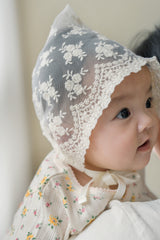 Side profile of baby girl wearing Avauma Clare Bonnet in Ivory Race, highlighting lace texture and gentle fit Side profile of baby girl wearing Avauma Clare Bonnet in Ivory Race, highlighting lace texture and gentle fit