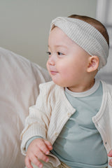 Close-up of a smiling baby wearing a headband – the Avauma Cloud Ribbed Setup in Sage Leaf paired with a matching cardigan creates a soft, tonal outfit Close-up of a smiling baby wearing a headband – the Avauma Cloud Ribbed Setup in Sage Leaf paired with a matching cardigan creates a soft, tonal outfit