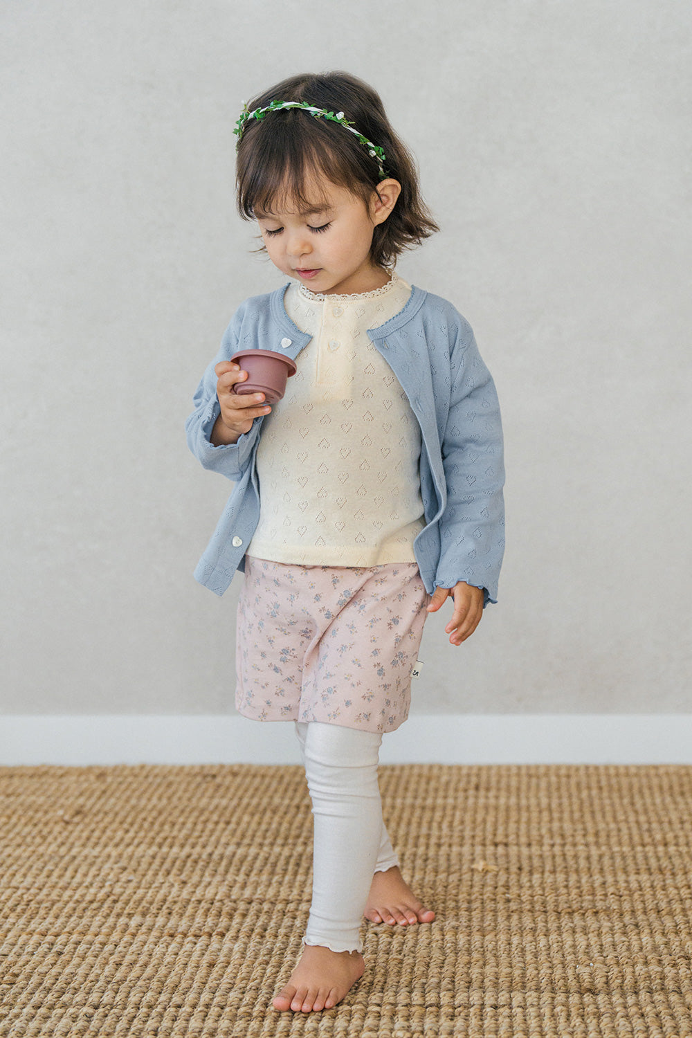 Toddler walking while wearing Avauma cream pink floral skirt leggings and holding a toy cup Toddler walking while wearing Avauma cream pink floral skirt leggings and holding a toy cup