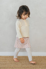 Side view of a toddler in Avauma flower skirt leggings in cream pink, showing full outfit with beige top Side view of a toddler in Avauma flower skirt leggings in cream pink, showing full outfit with beige top