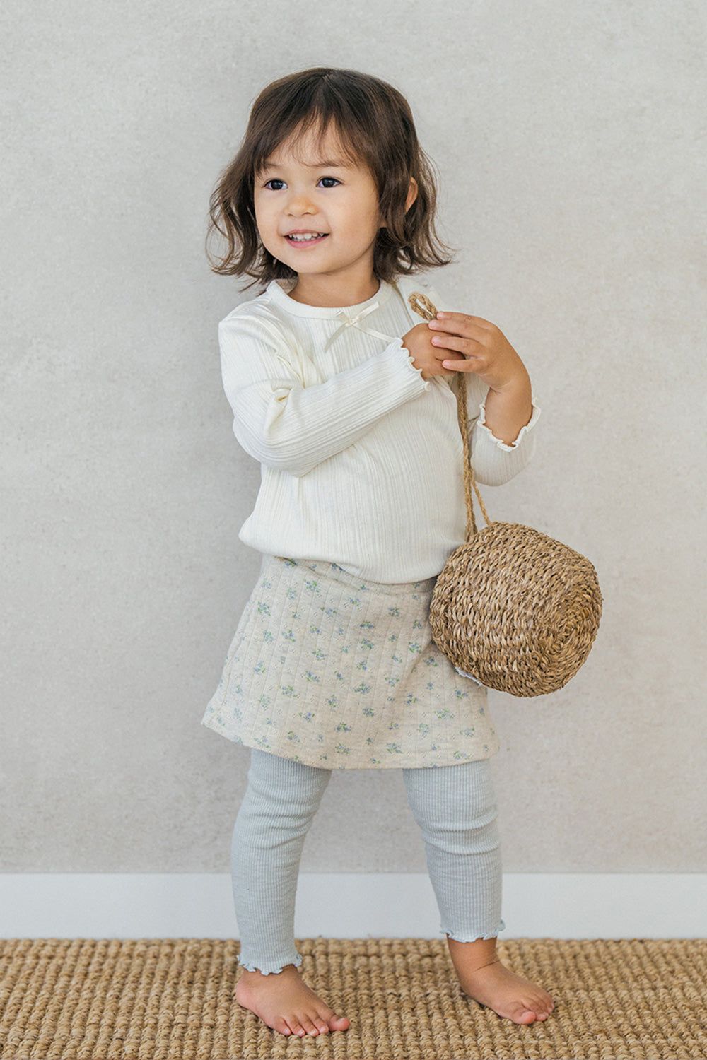 Toddler girl wearing Avauma baby skirted leggings in mint green with floral print, styled with ivory ribbed top Toddler girl wearing Avauma baby skirted leggings in mint green with floral print, styled with ivory ribbed top