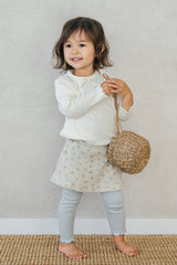 Toddler girl wearing Avauma baby skirted leggings in mint green with floral print, styled with ivory ribbed top Toddler girl wearing Avauma baby skirted leggings in mint green with floral print, styled with ivory ribbed top