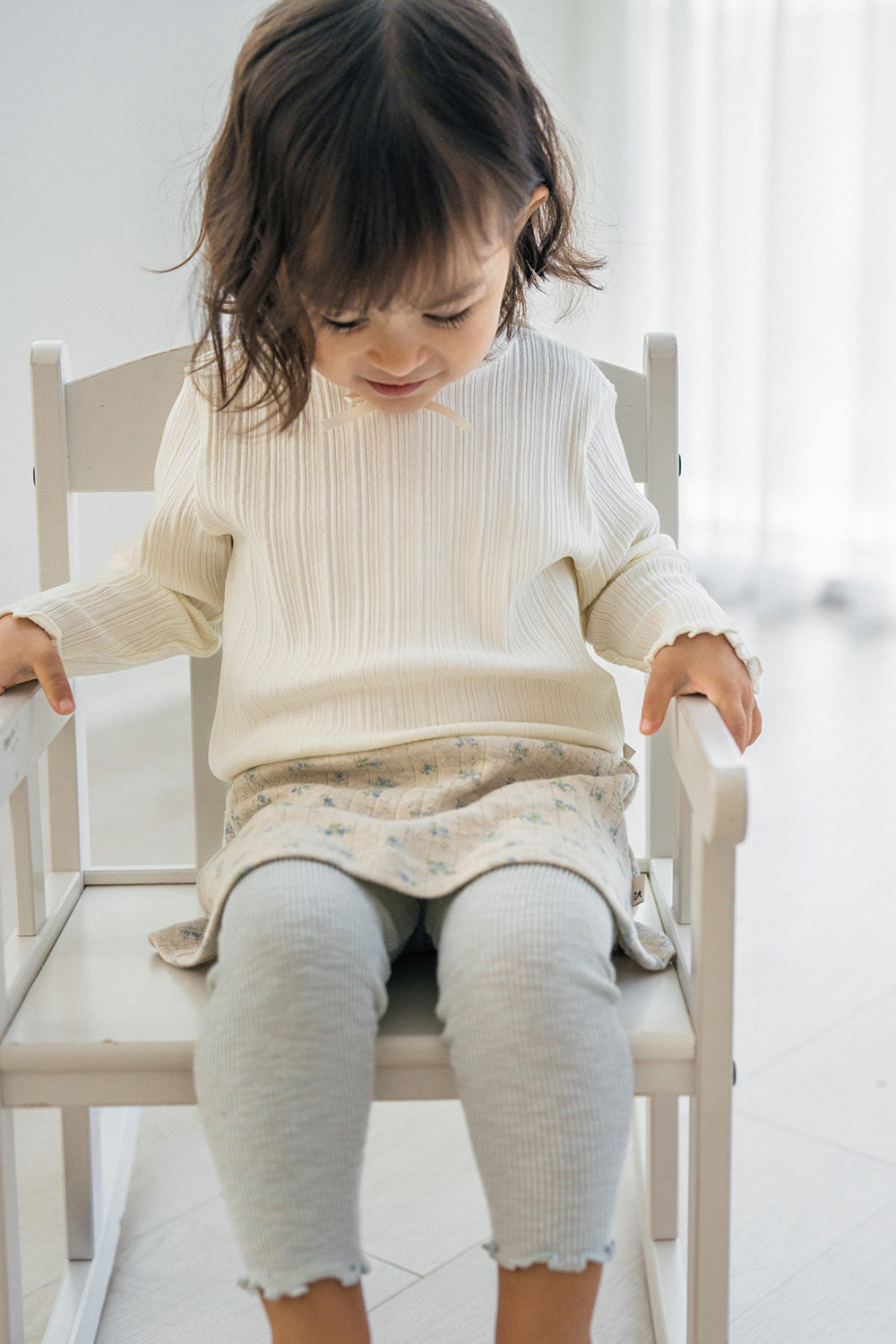 Baby girl sitting on chair wearing Avauma mint green baby skirt leggings and ribbed ivory top Baby girl sitting on chair wearing Avauma mint green baby skirt leggings and ribbed ivory top