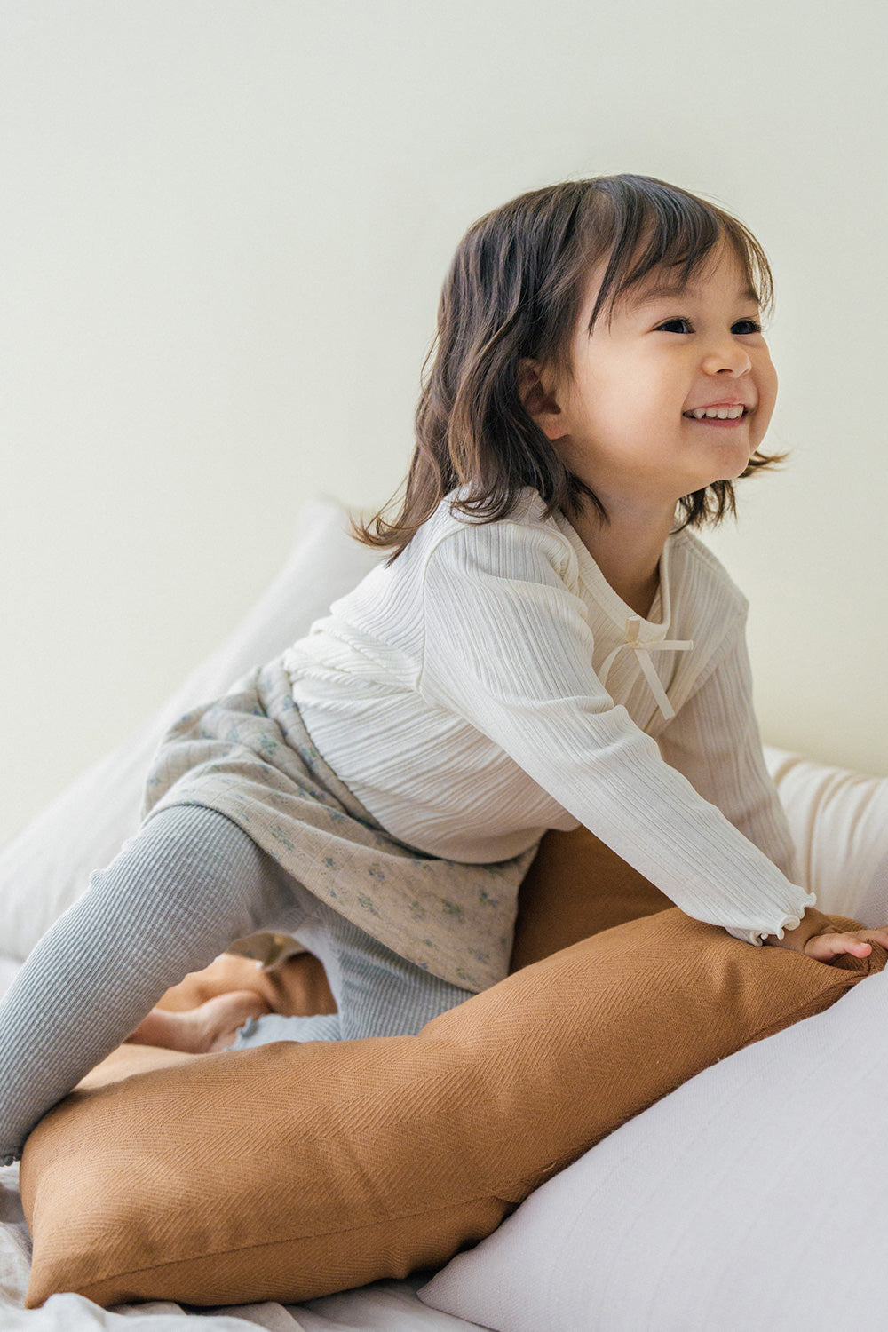 Smiling baby girl wearing Avauma mint green baby skirted leggings while playing on bed Smiling baby girl wearing Avauma mint green baby skirted leggings while playing on bed