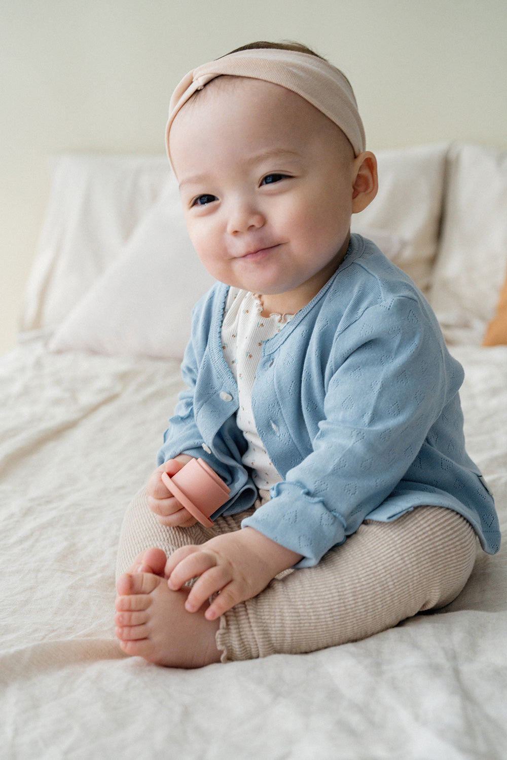 Smiling baby in Avauma blue cotton cardigan, cozy baby outfit with heart knit details for girls and boys Smiling baby in Avauma blue cotton cardigan, cozy baby outfit with heart knit details for girls and boys